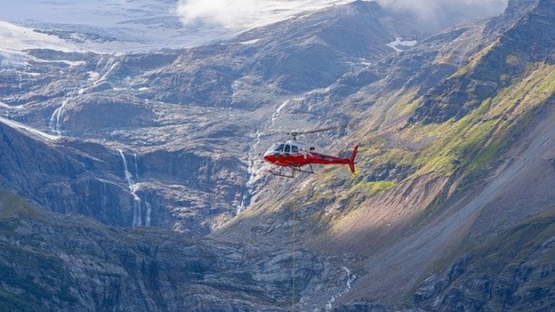 A red helicopter flying in a mountainous region