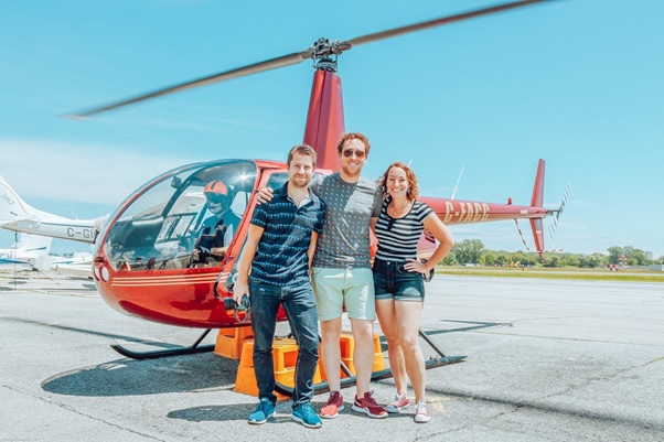 Three friends standing in front of a helicopter